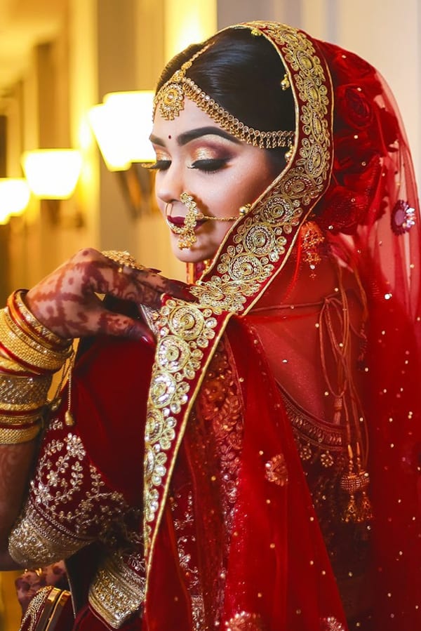 A woman in red and gold is putting on her makeup.