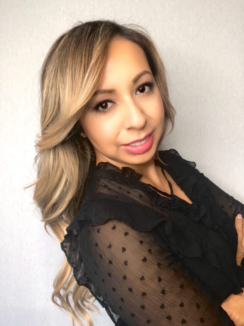 A woman with long blonde hair wearing black.